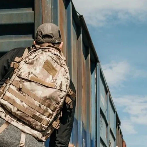 Traveler with a Highland Tactical Backpack on a train looking towards adventure.