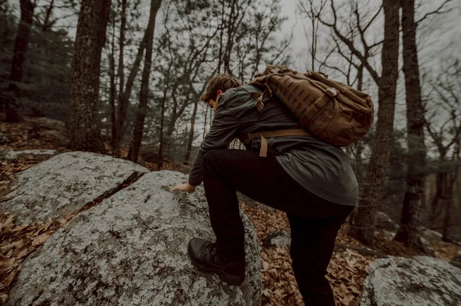A man in the woods with a tactical backpack.